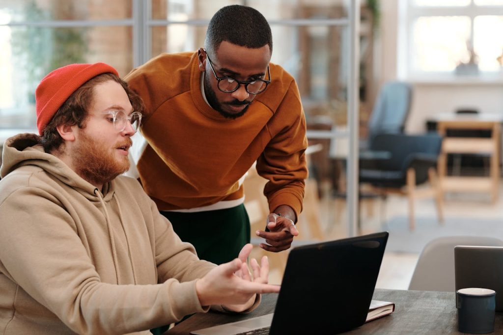 men-looking-at-the-screen-of-a-laptop-6147360 Diverse colleagues brainstorming together in a modern office, fostering teamwork and creativity.